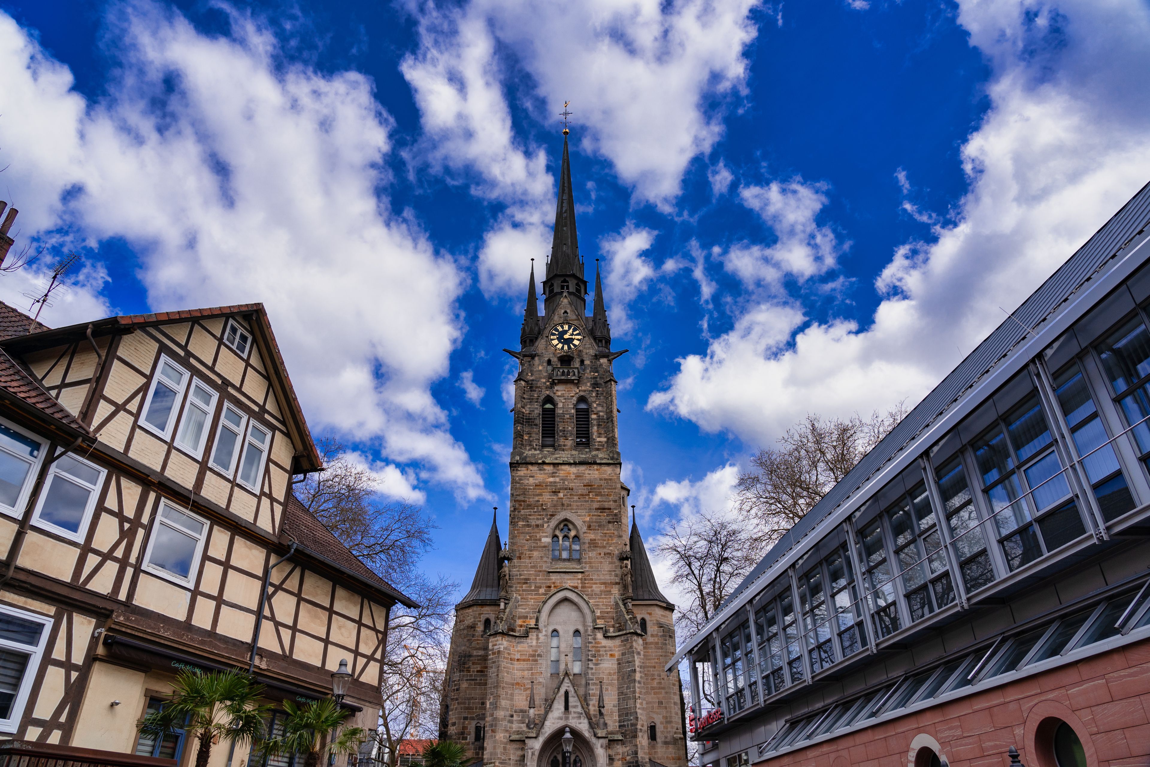 A church with a tall spire and a clock, surrounded by traditional half-timbered houses.