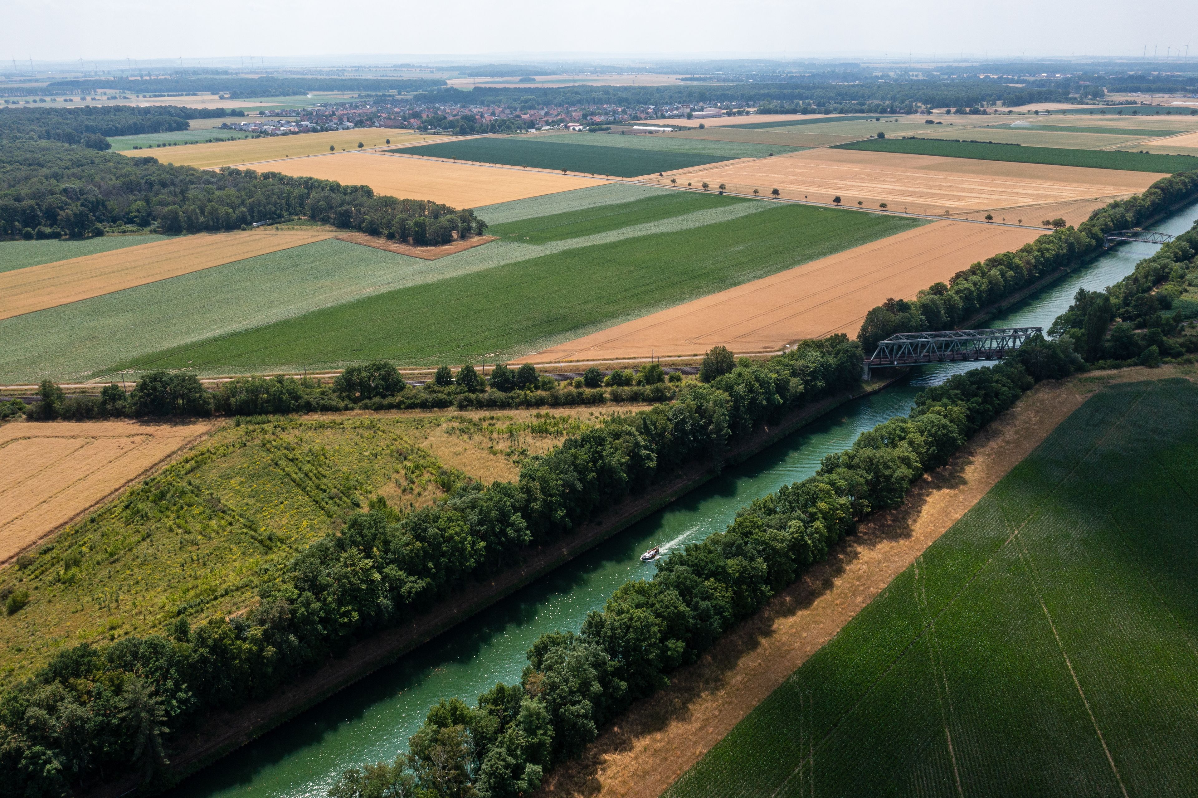 A river with a bridge, surrounded by agricultural fields and a distant town.