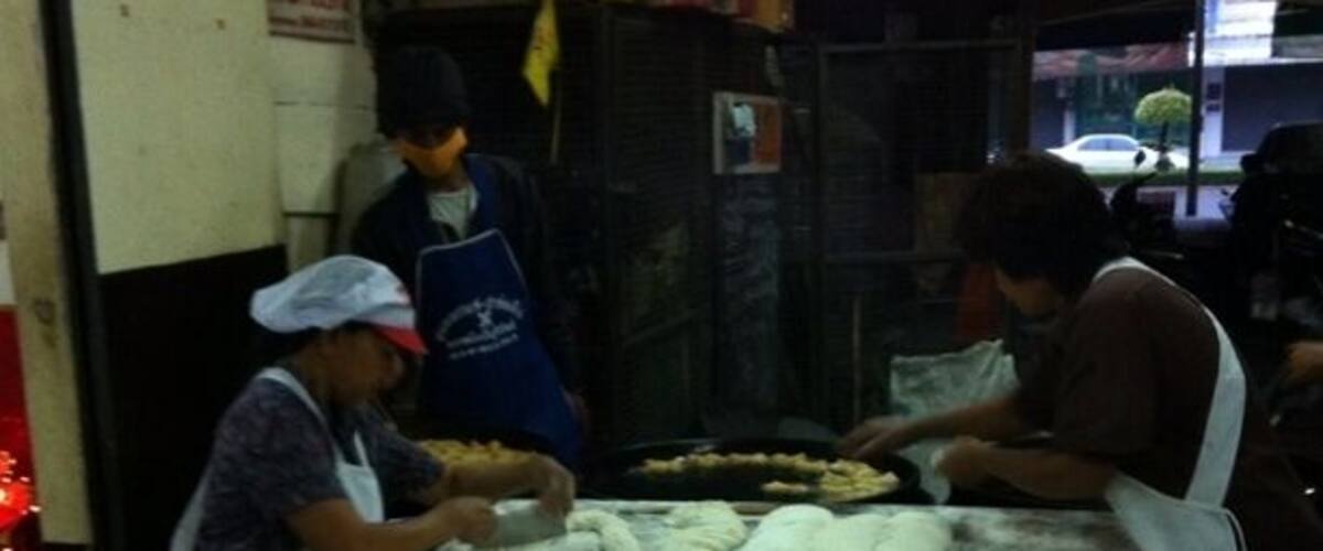 A dough preparation area with workers, a large table, and a blue bowl.