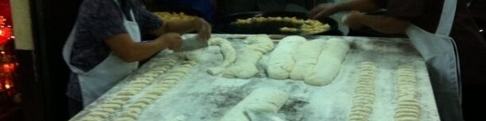 A dough preparation area with workers, a large table, and a blue bowl.