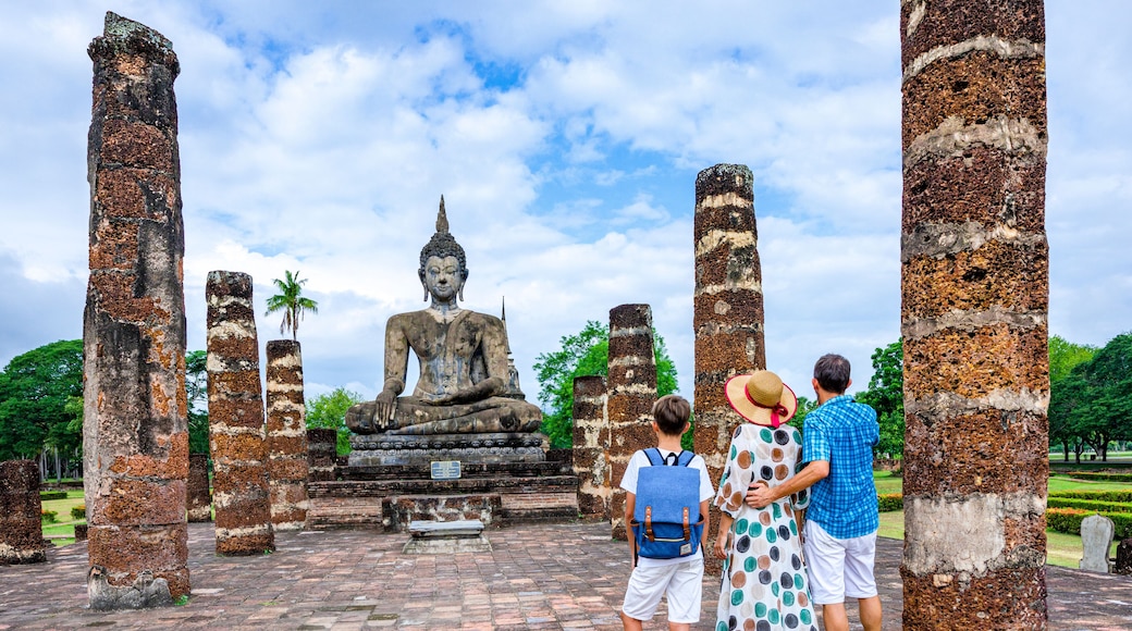 Happy family with one boy looking at a Buddha statue in an old temple