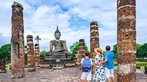 Happy family with one boy looking at a Buddha statue in an old temple