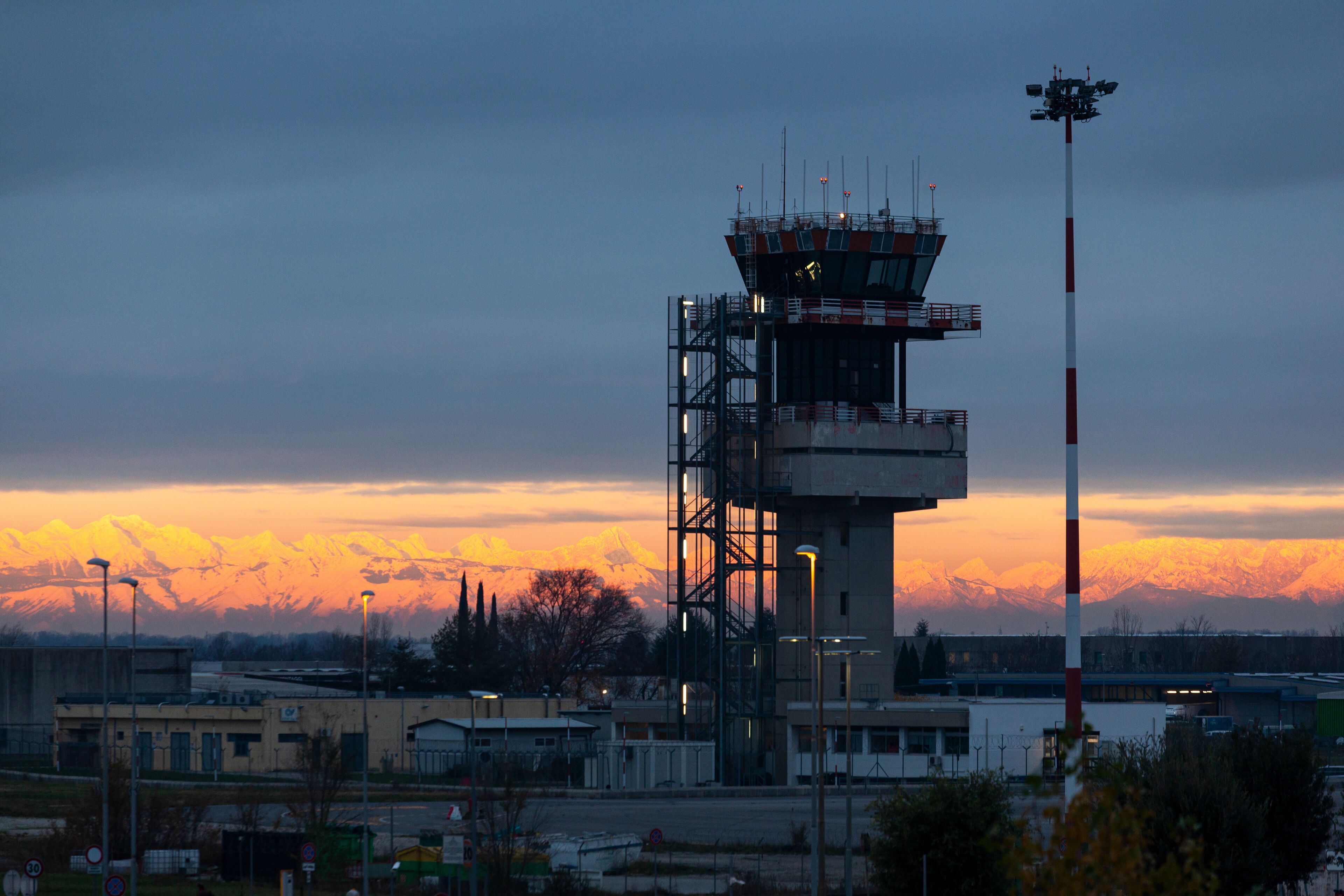 A control tower with a mountain range in the background during sunset.