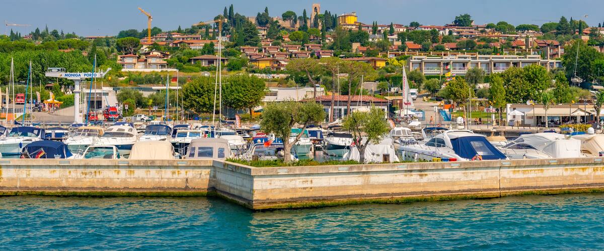 A marina with boats, a coastal town with buildings, and a clear blue sky.