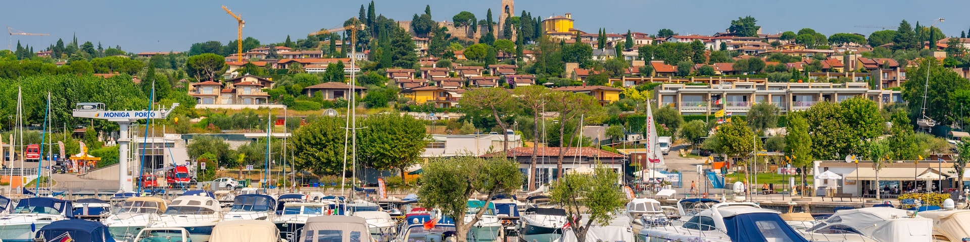 A marina with boats, a coastal town with buildings, and a clear blue sky.