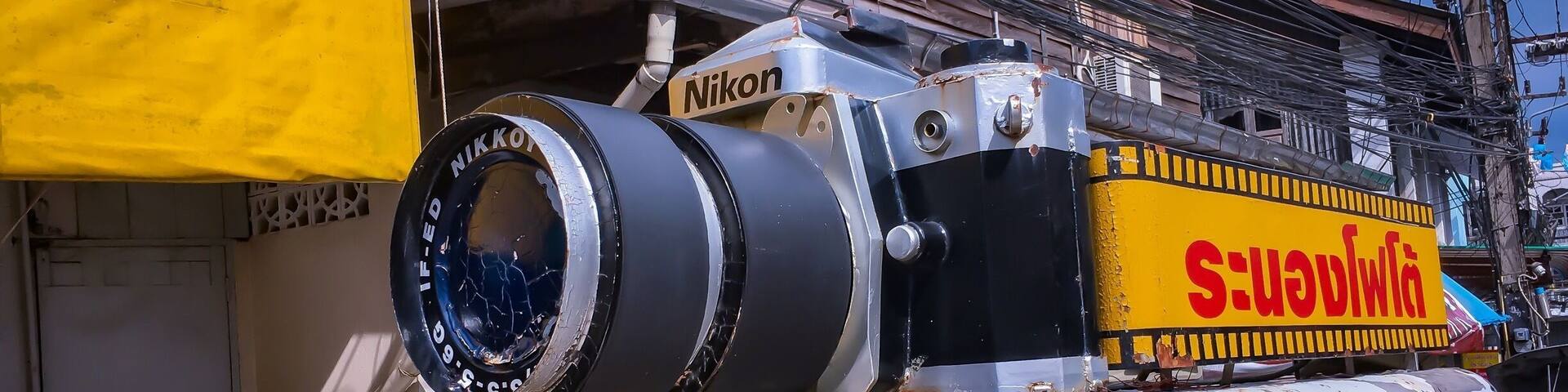 A truck with a large camera on top and a sign that reads "Nikon".