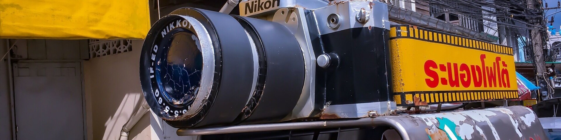 Um caminhão com uma câmera grande no topo e um letreiro com a inscrição 'Nikon'.