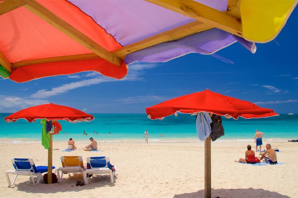 Ein Strand mit mehreren bunten Sonnenschirmen und Liegestühlen.