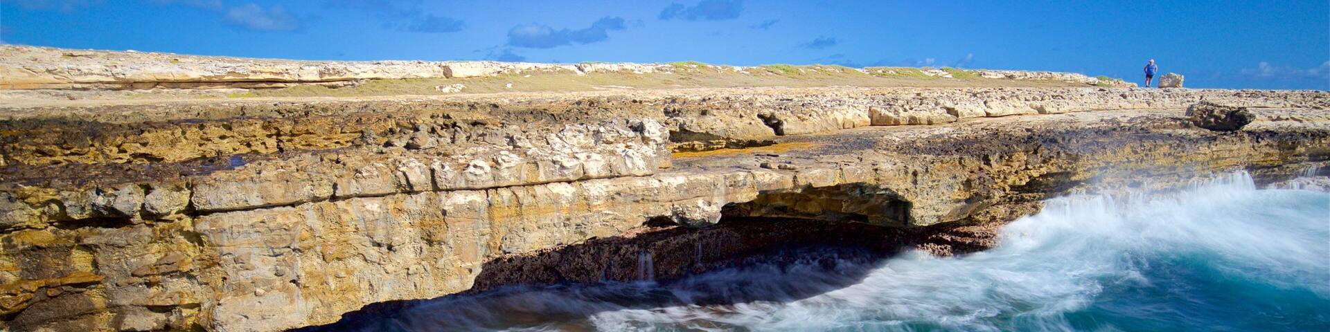 A coastal rock formation with a waterfall and turquoise waters.
