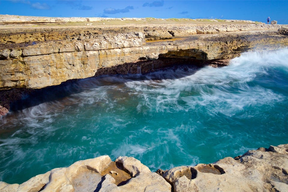 A coastal rock formation with a waterfall and turquoise waters.