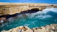 Une formation rocheuse côtière avec une cascade et des eaux turquoise.