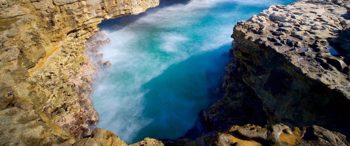 A coastal rock formation with a narrow passage leading into the sea.