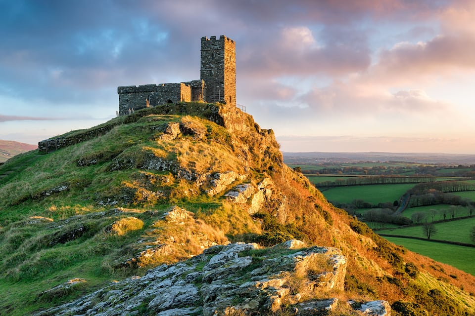 Un château de pierre historique, perché sur une colline verdoyante, d’où l’on peut admirer une vue dégagée sur la campagne environnante.