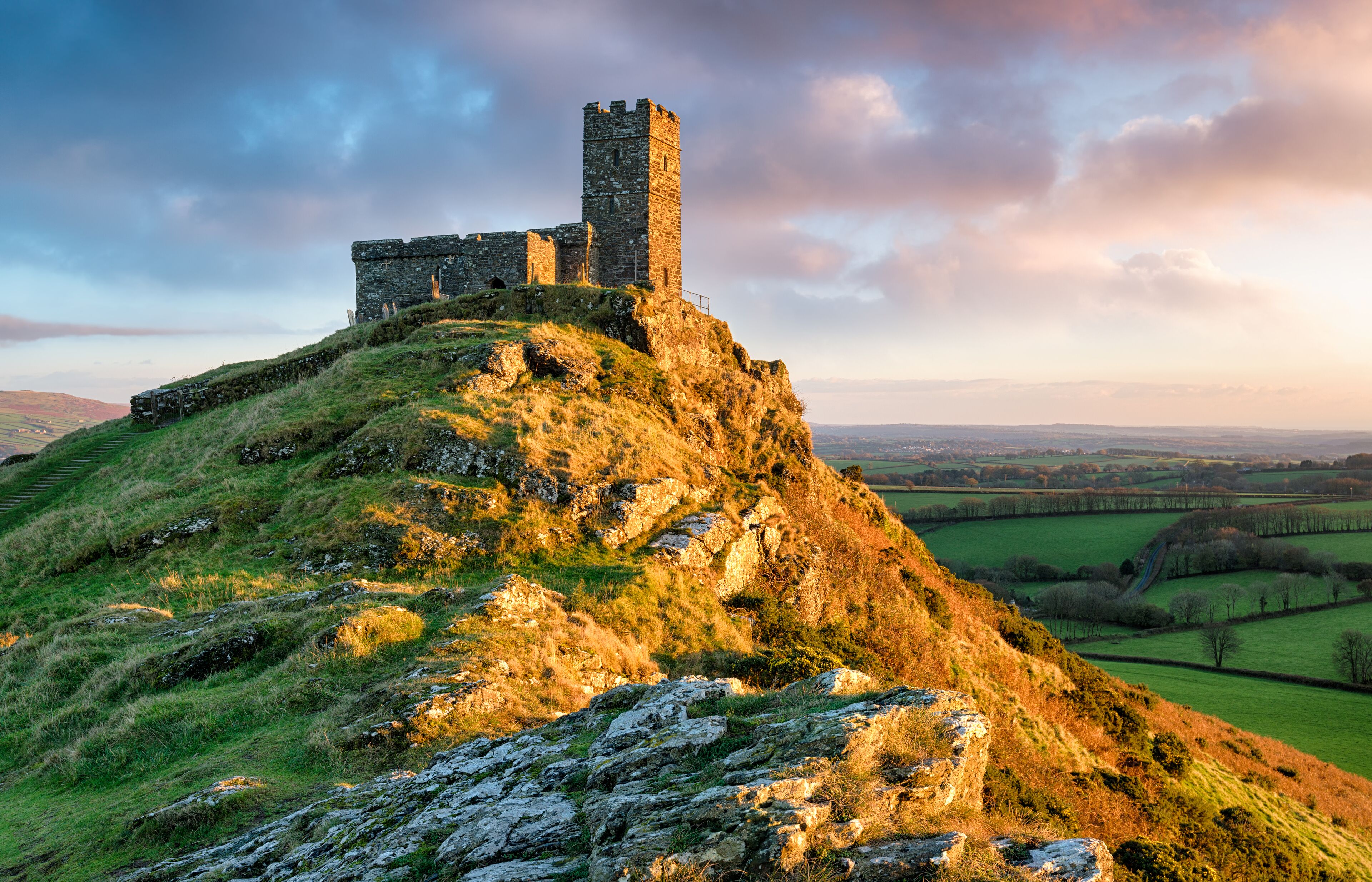 A historic stone castle on a grassy hill with a clear view of the surrounding countryside.