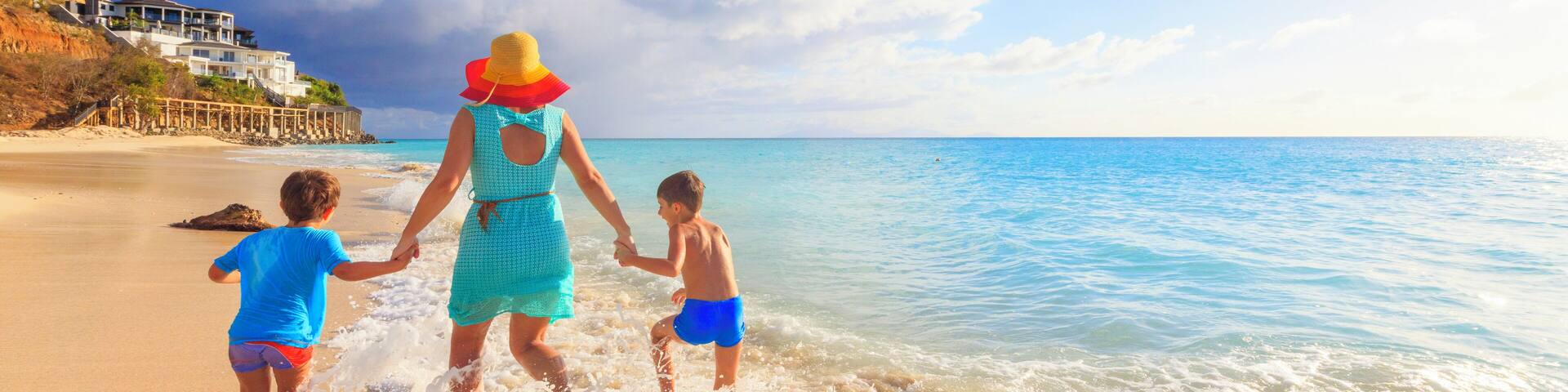 Mother and sons having fun with sea waves, Ffryes Beach, Antigua, Antigua and Barbuda, Leeward Islands, West Indies