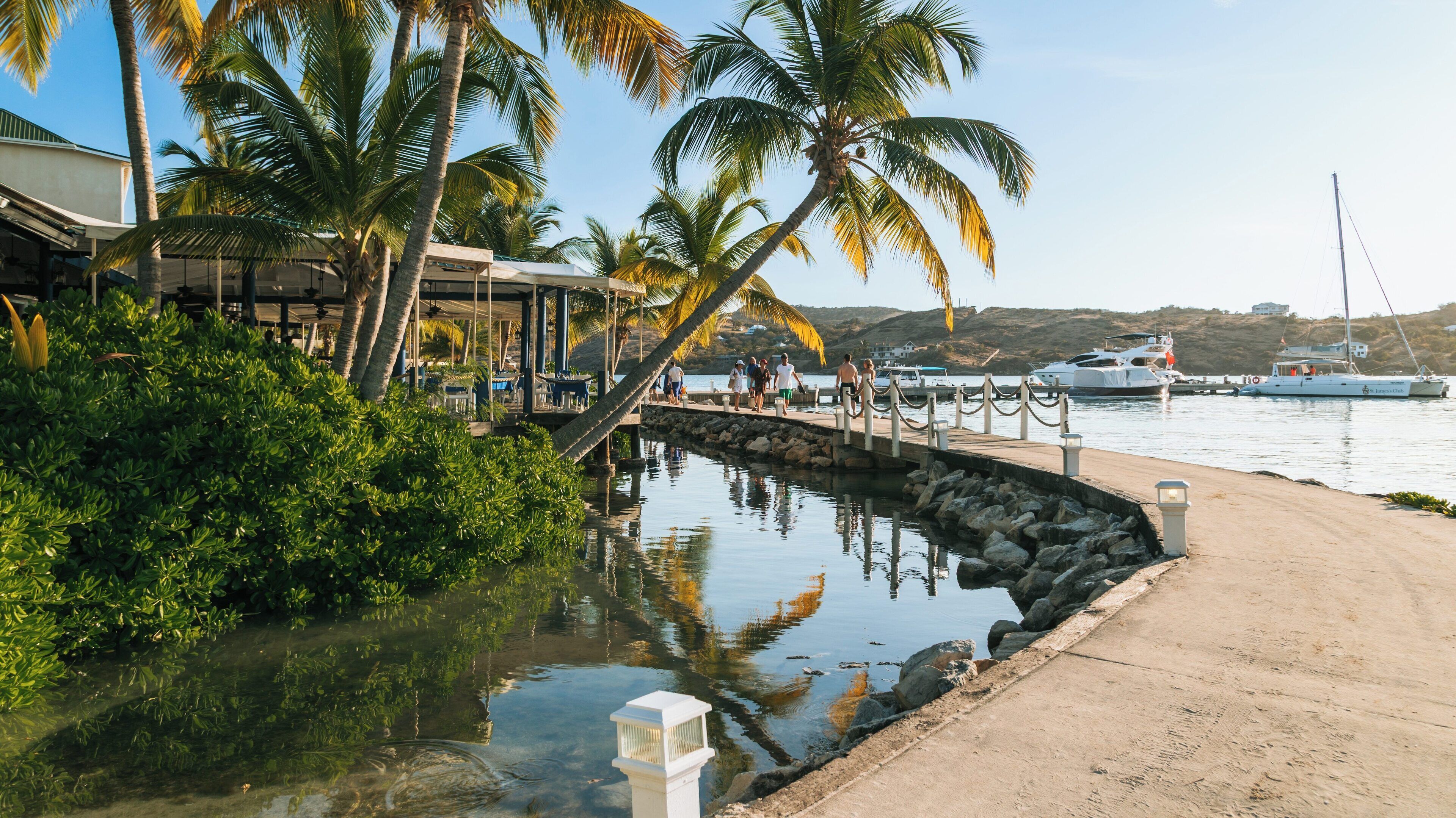 Stunning view of Mamora Bay at English Harbour showcasing calm waters and lush palm trees under clear skies