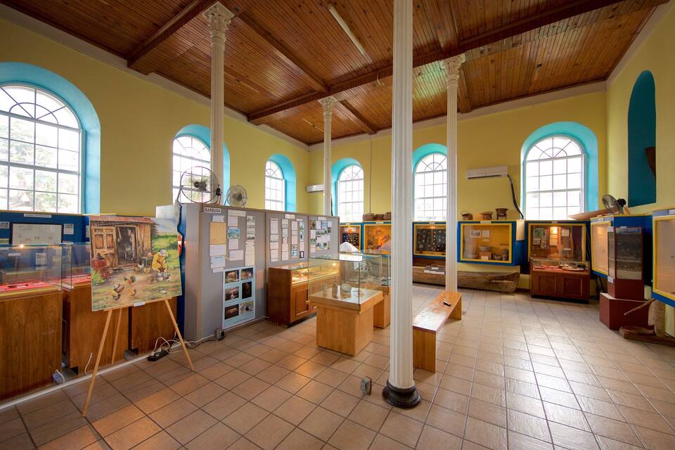 A museum with wooden beams, arched windows, and display cases.
