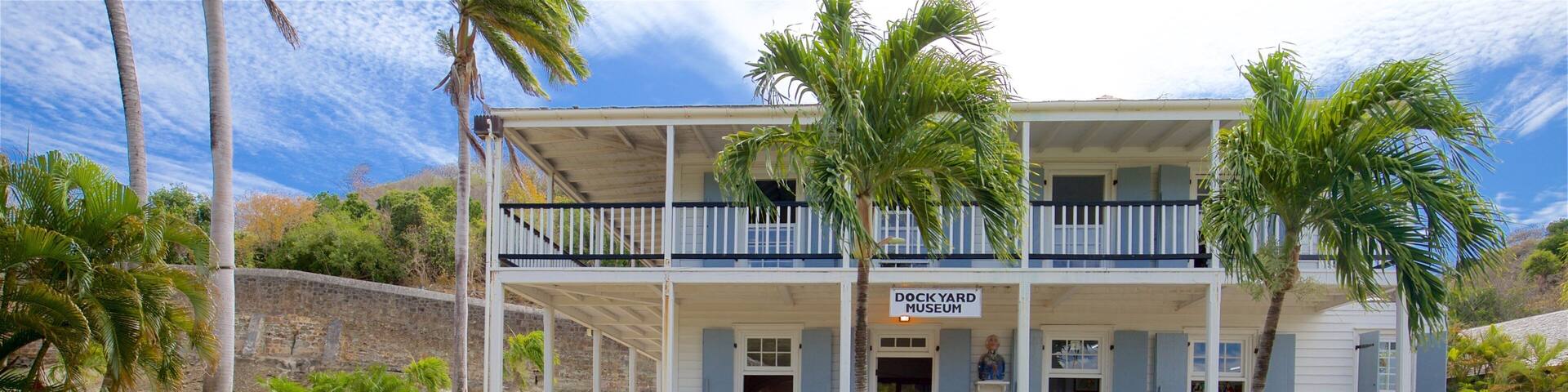 A historic building with a sign reading "Dockyard Museum" surrounded by palm trees and a cannon.