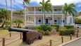 A historic building with a sign reading "Dockyard Museum" surrounded by palm trees and a cannon.