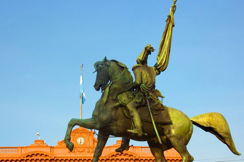 Una statua equestre in bronzo con un'asta di bandiera sullo sfondo.