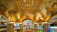 A shopping mall with a grand, arched ceiling featuring classical frescoes.