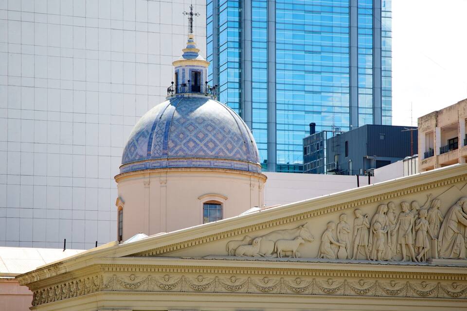 A domed building with intricate sculptures and a modern glass skyscraper in the background.