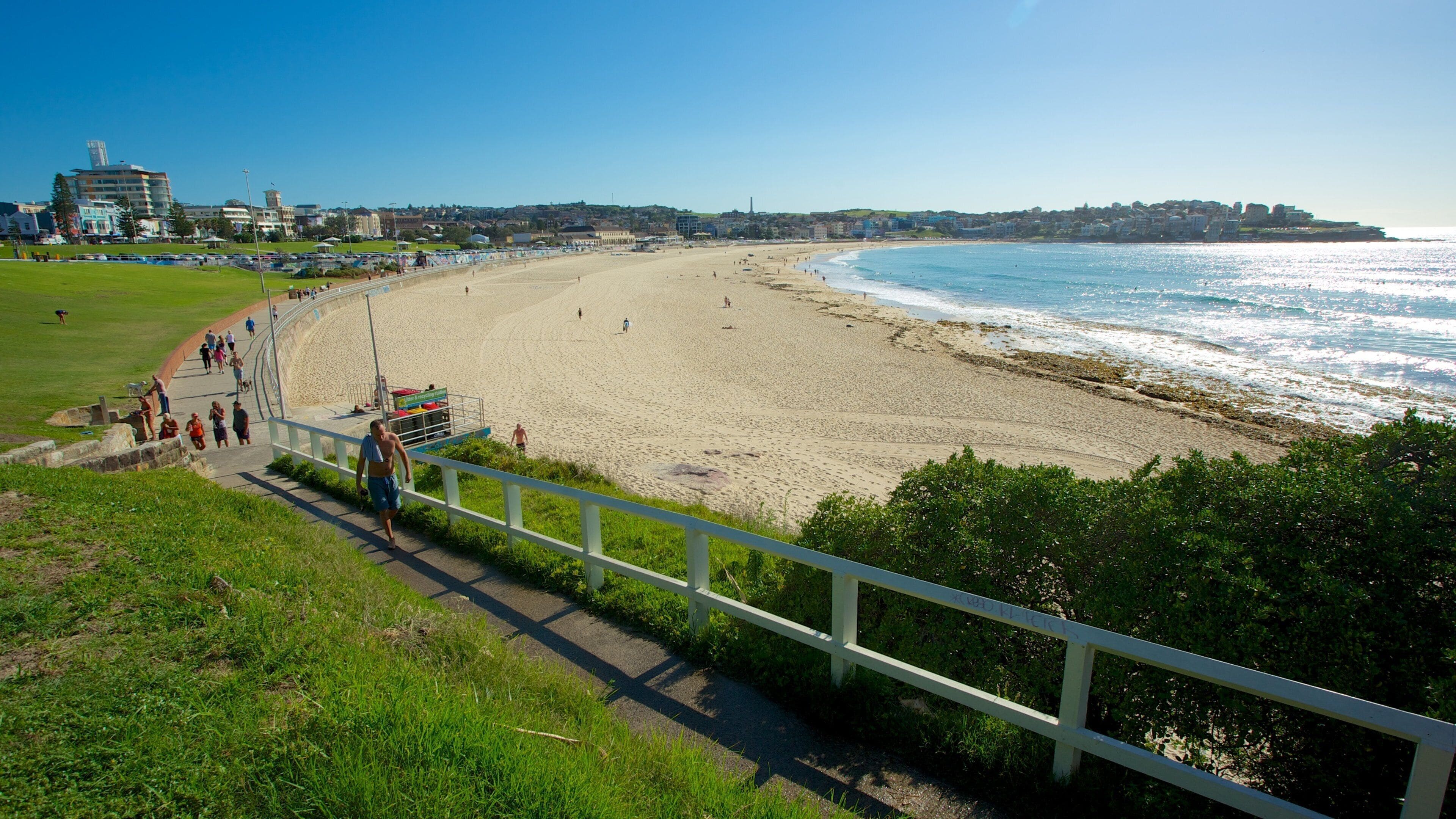 A coastal beach with a promenade, ocean waves, and buildings in the background.
