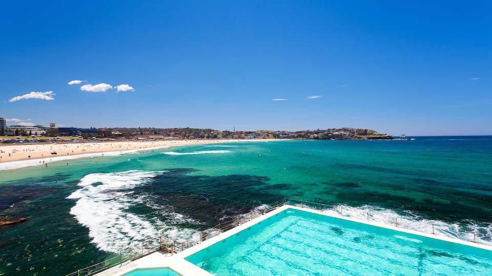 Un paisaje costero con playa, piscina y cielo azul despejado.