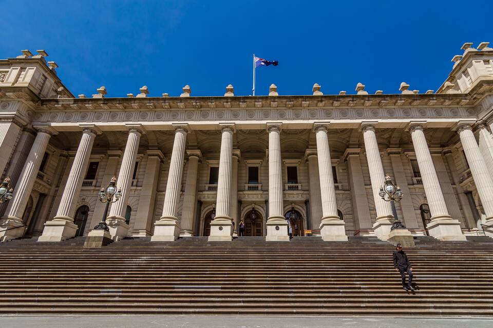 A grand building with large columns and a flag on top.