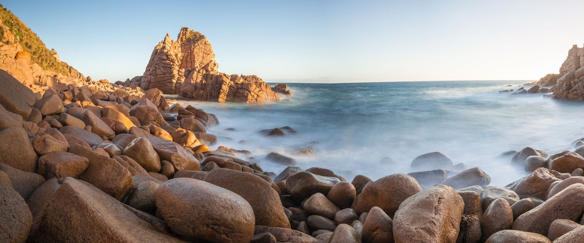 A rocky coastline with large boulders and towering rock formations.