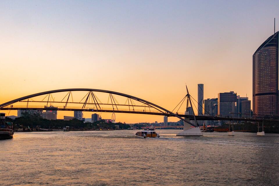 A bridge over water with a city skyline in the background.