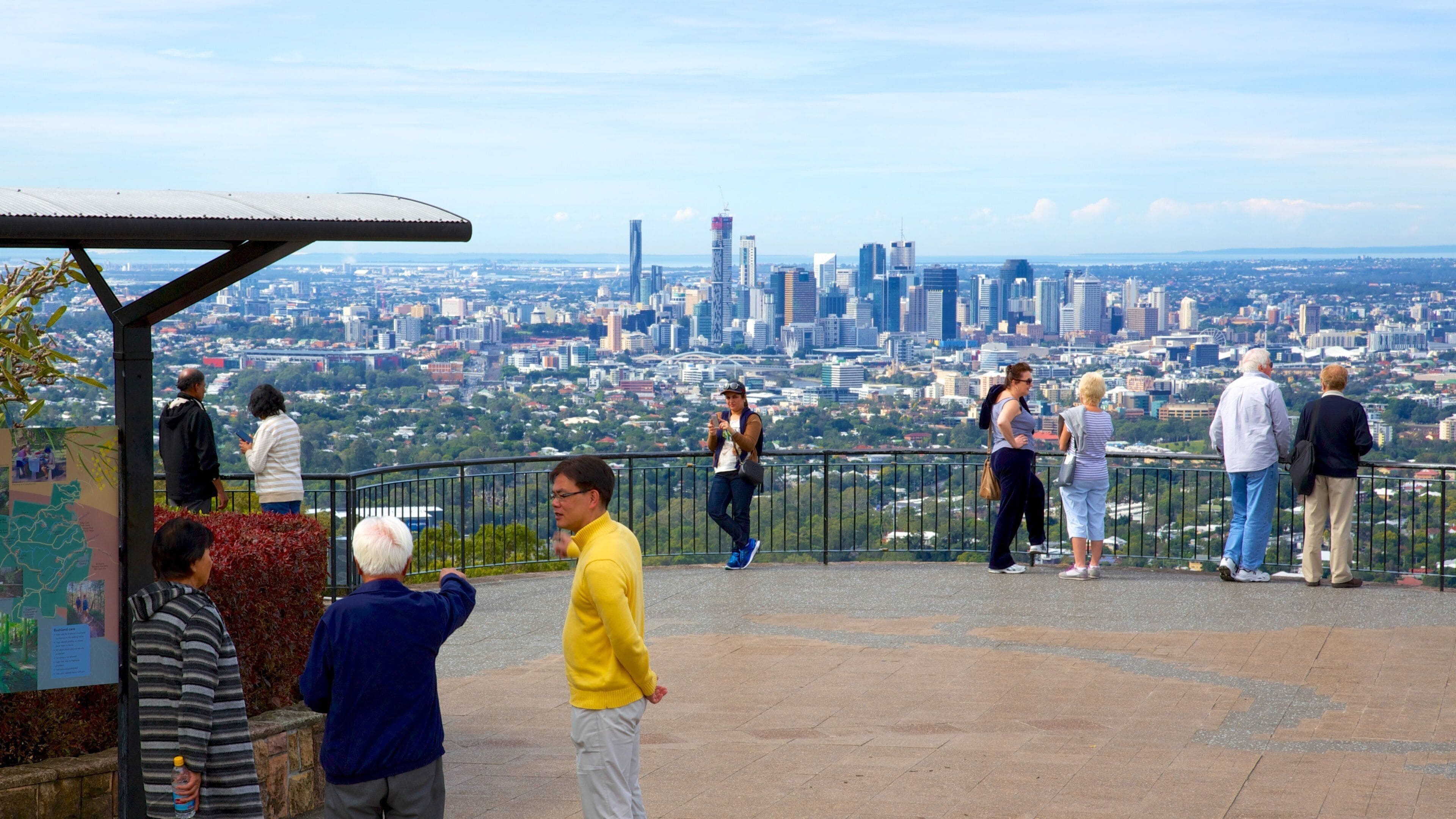 A panoramic view of a cityscape from a high vantage point, including a prominent skyscraper and a Ferris wheel.