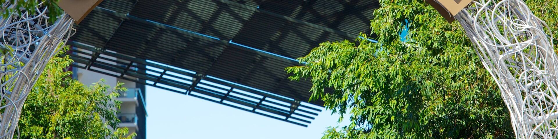 A sign for Queen Street Mall with a modern architectural structure in the background.