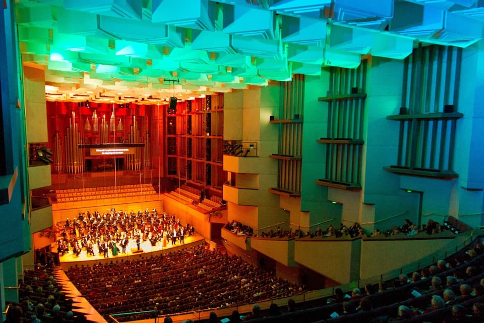 Een concertzaal met terrassen, een podium en een groot orkest.
