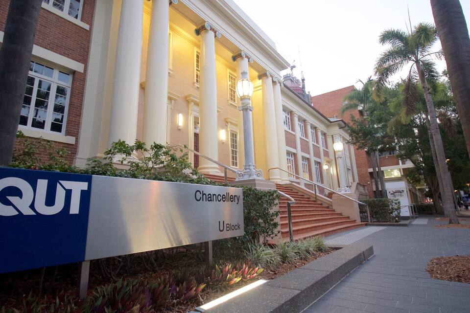 A building with a sign reading "Chancellery U Block" and a "QUT" sign.