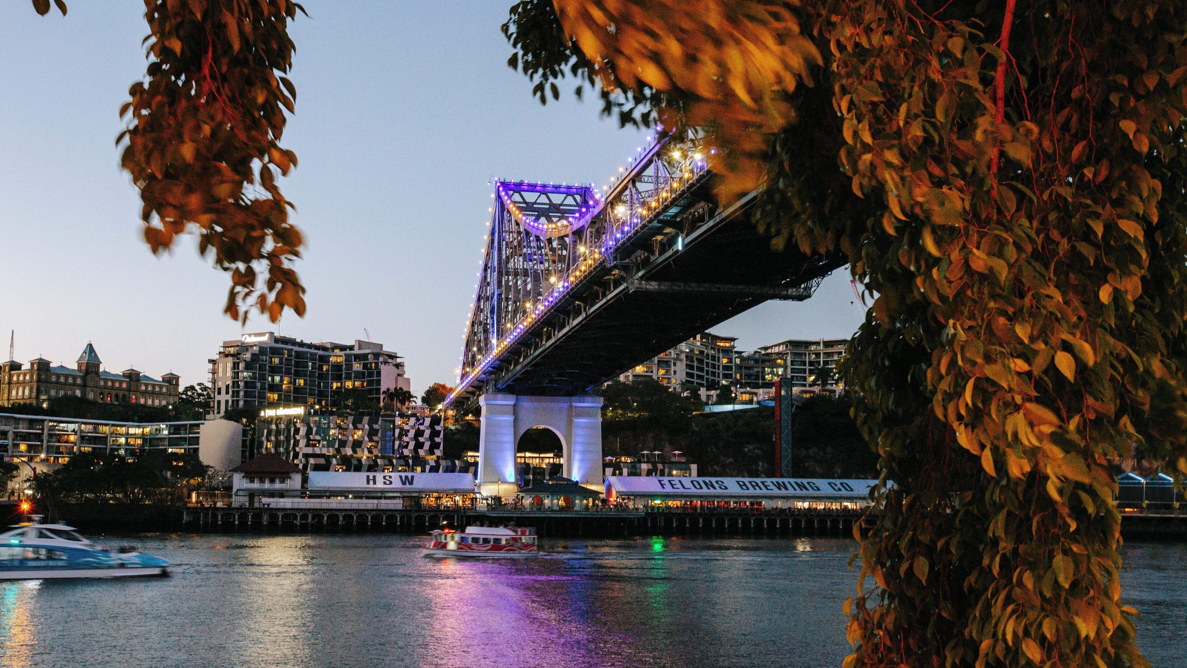 Vibrant evening view of Story Bridge illuminating the Brisbane River at Kangaroo Point in Queensland, Australia with city lights reflecting on the water