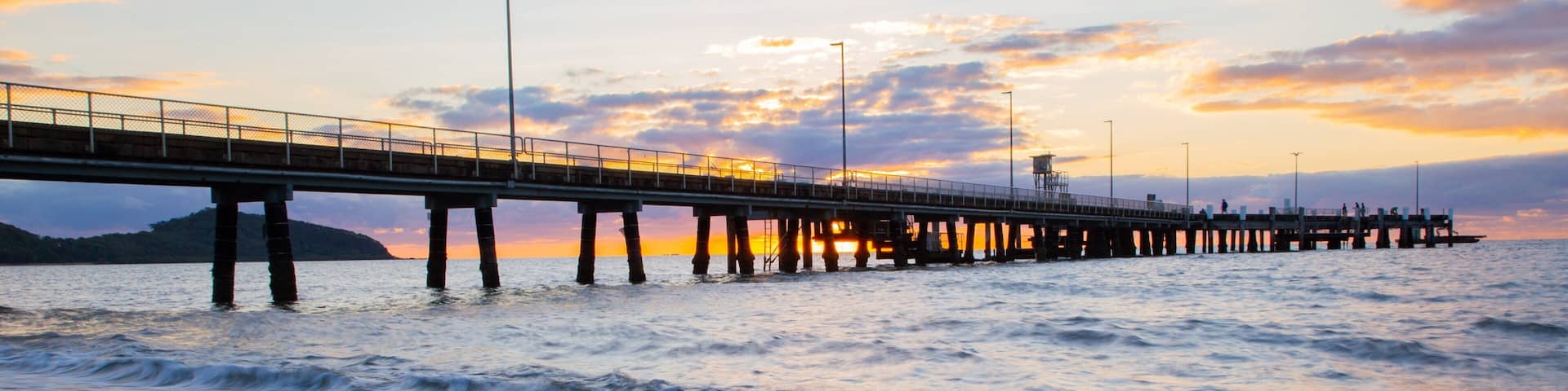 A pier extending into the ocean at sunset.