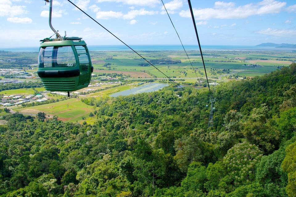 Teleférico sobre uma paisagem verdejante com rio e montanhas ao longe.