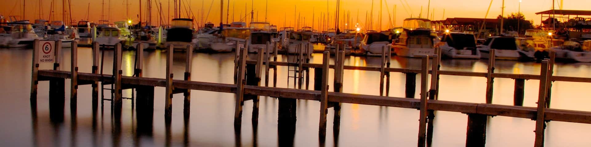 Hillarys Boat Harbour showing a coastal town, a sunset and a bay or harbor