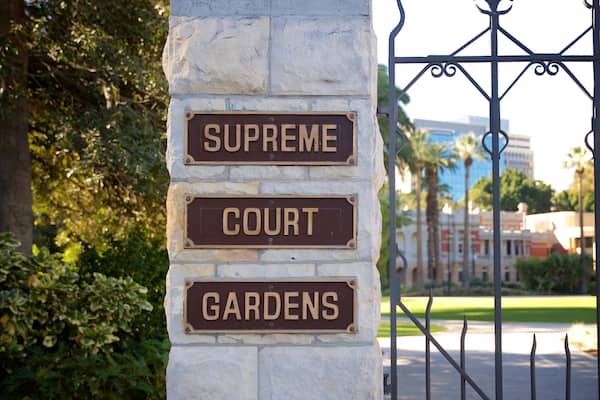 A stone pillar with signs reading "Supreme Court" and "Gardens".