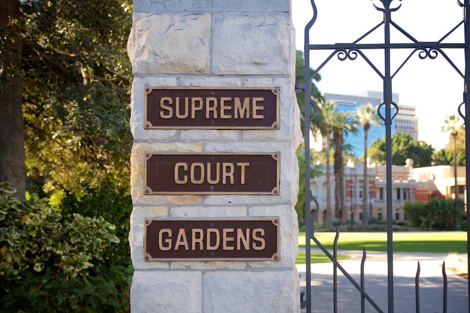 A stone pillar with signs reading "Supreme Court" and "Gardens".