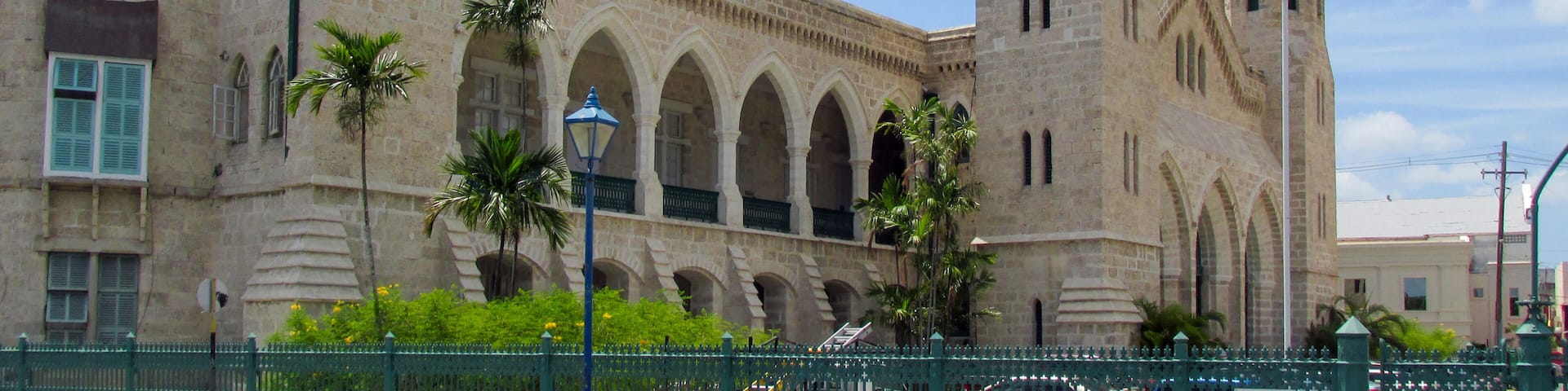 A historic building with a clock tower, arched windows, and a flag.