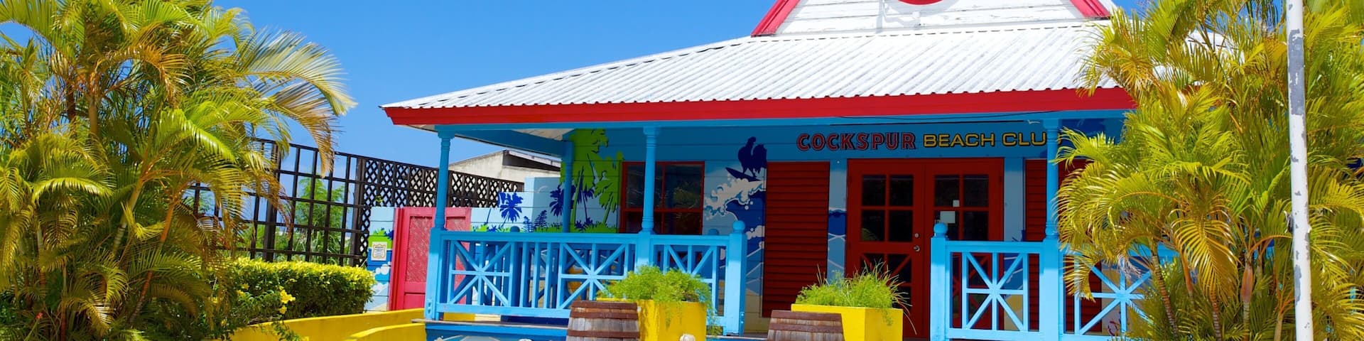 A colorful building with a red roof, blue and yellow walls, and a sign that reads "Cockspur Beach Club".