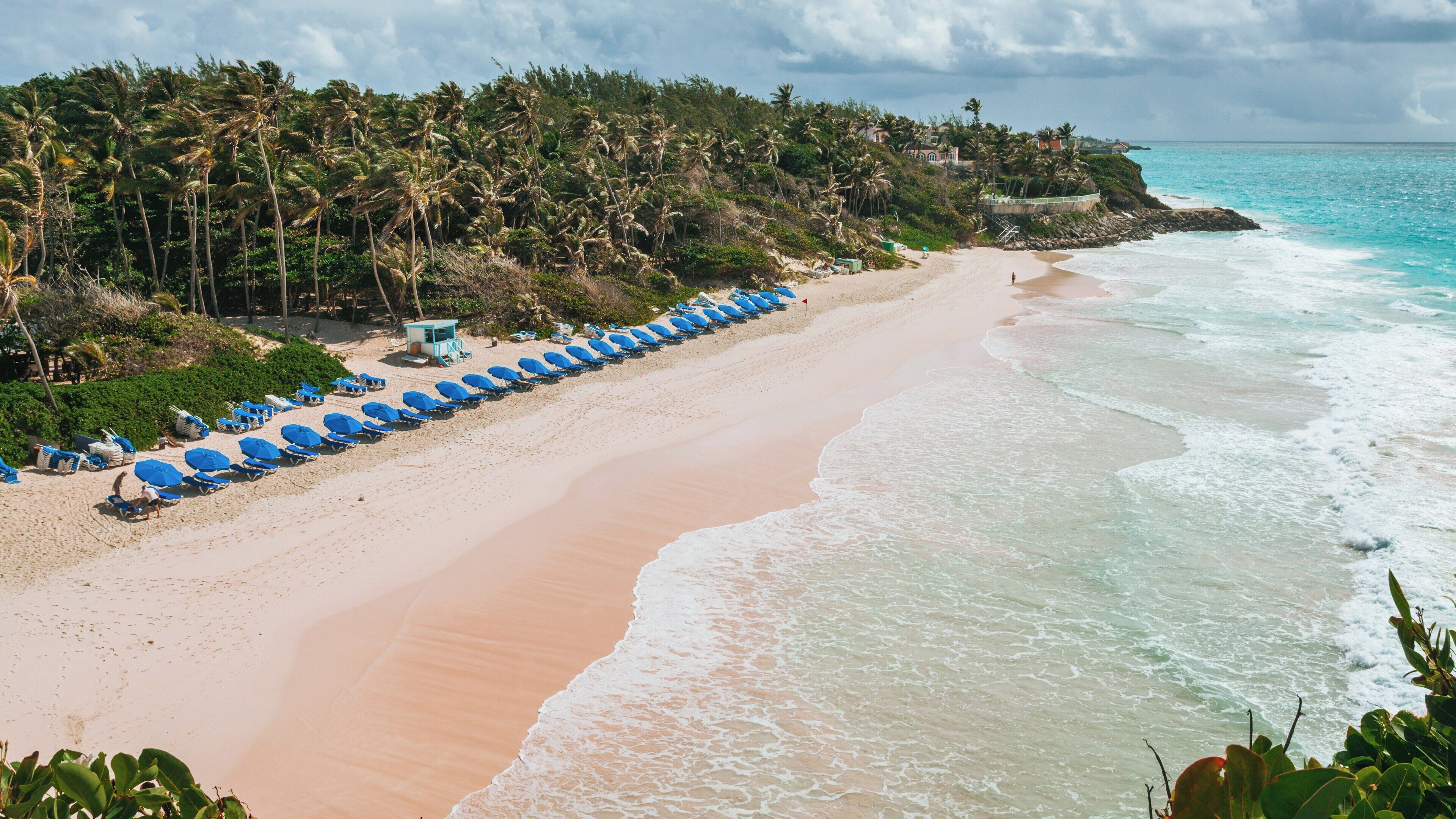 Relaxing day at Crane Beach in St. Philip, Barbados with blue umbrellas lining the shoreline