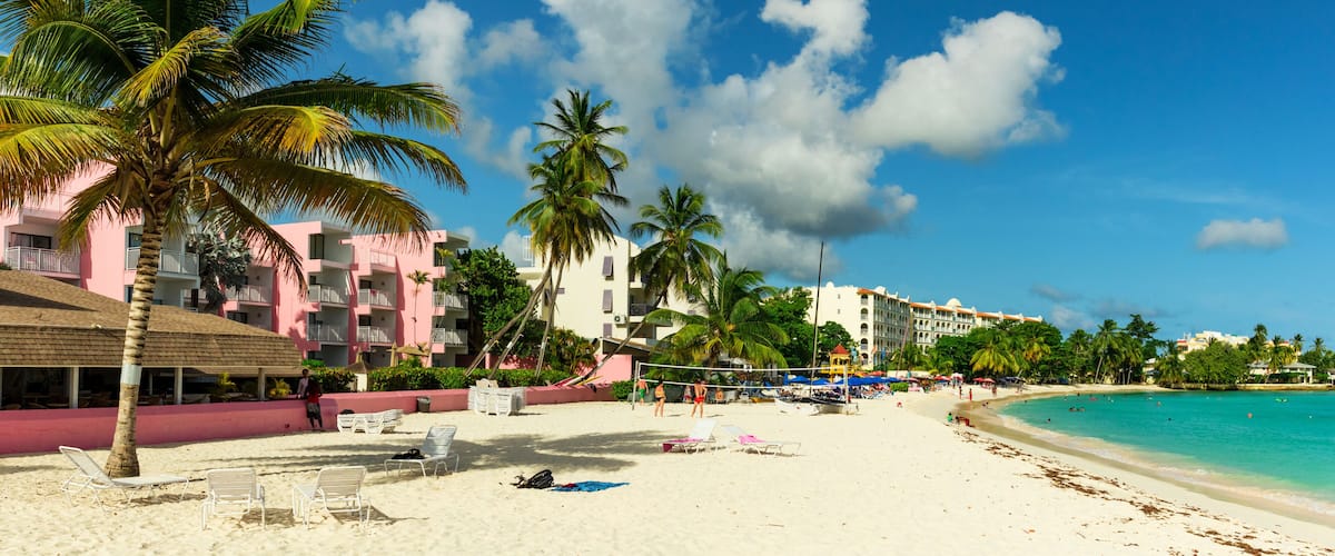 A beach with palm trees, a hotel, and a clear blue sky.