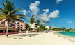 Een strand met palmbomen, een hotel en een helderblauwe lucht.