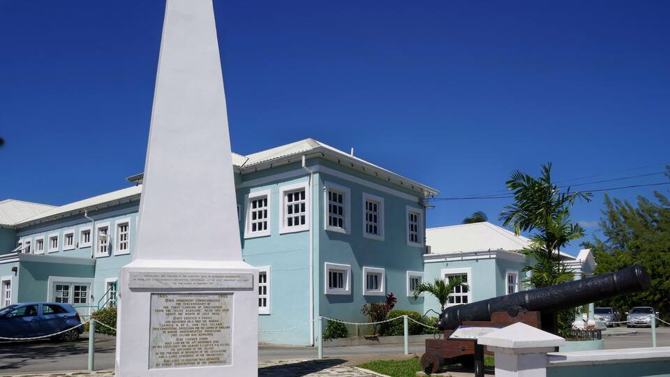 A monument, a light blue building, and a cannon.