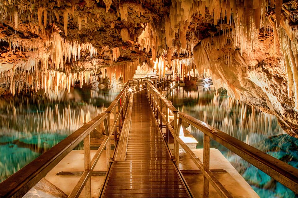 Eine Höhle mit Stalaktiten und einem hölzernen Steg über Wasser.