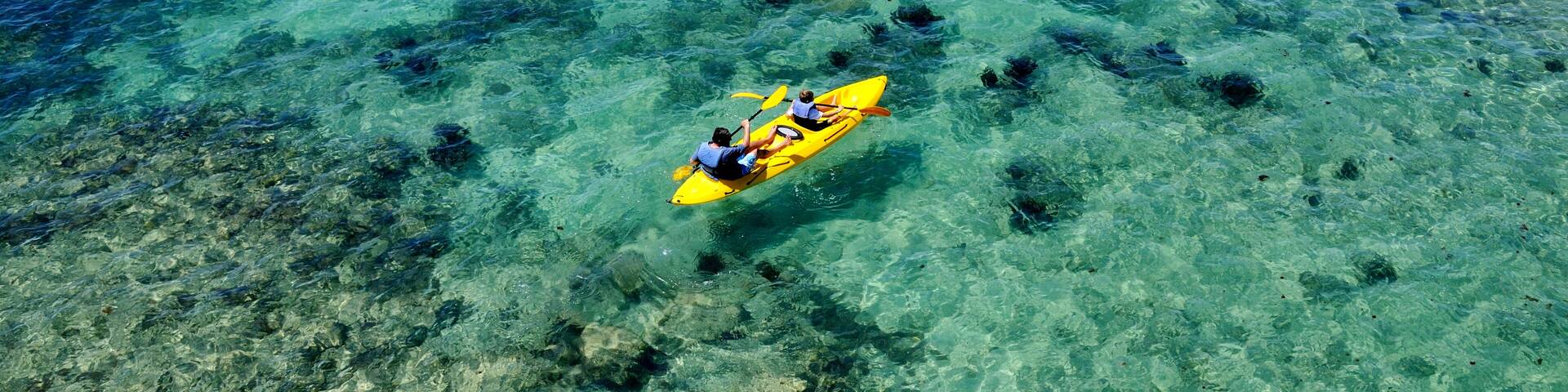 Father and son kayak the crystal clear blue waters of Bermuda by Fort Hamilton
