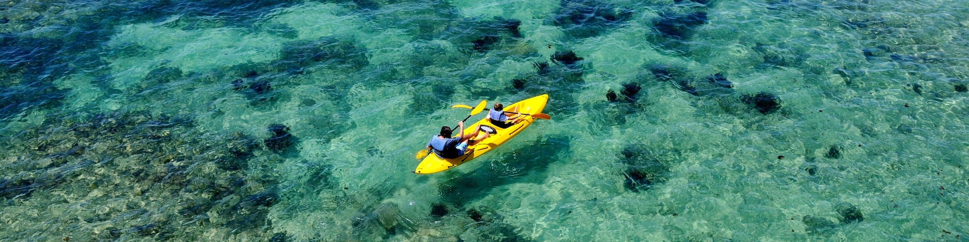 Father and son kayak the crystal clear blue waters of Bermuda by Fort Hamilton